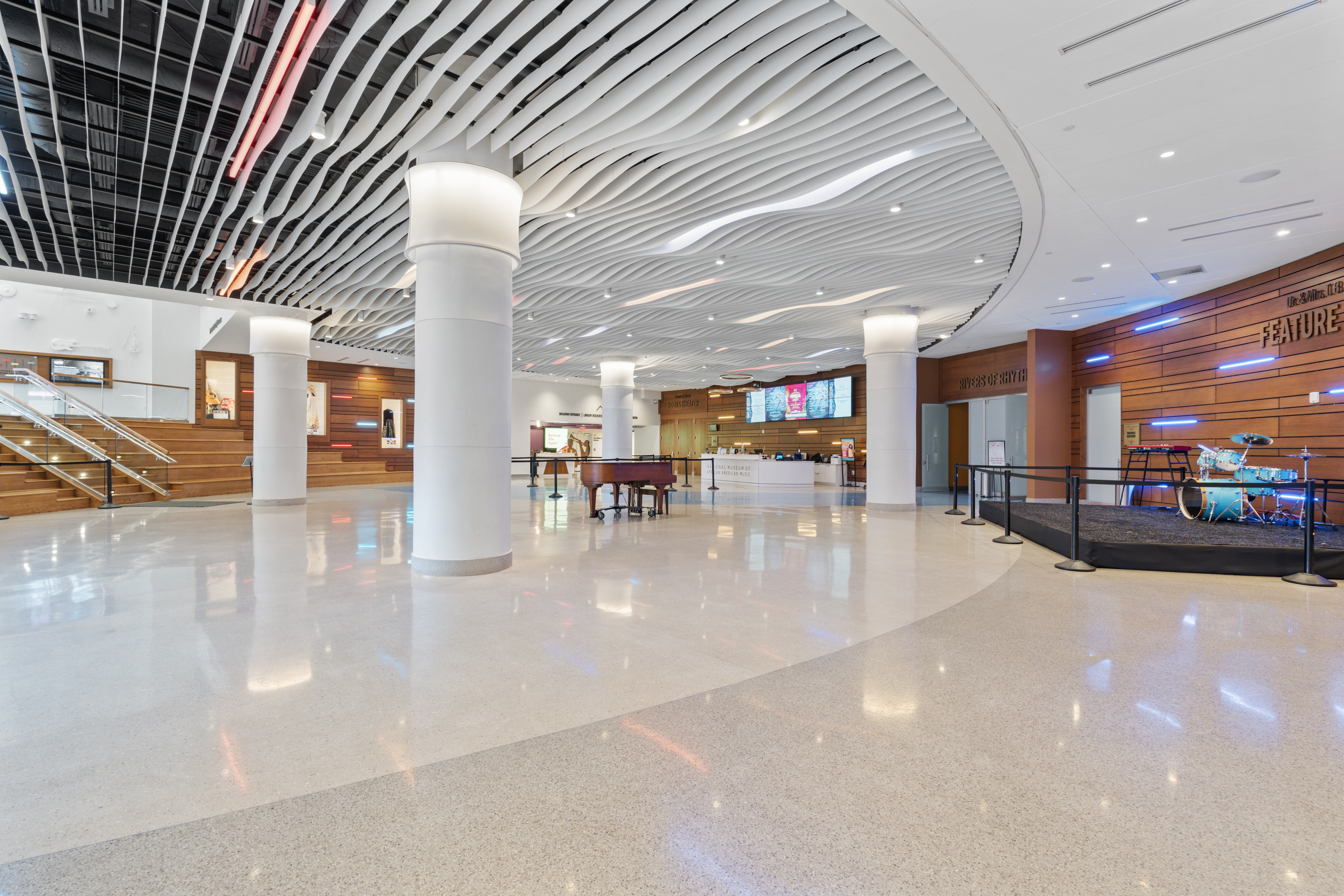National Museum of African American Music lobby concourse with wave ceiling, grand piano, and welcome desk